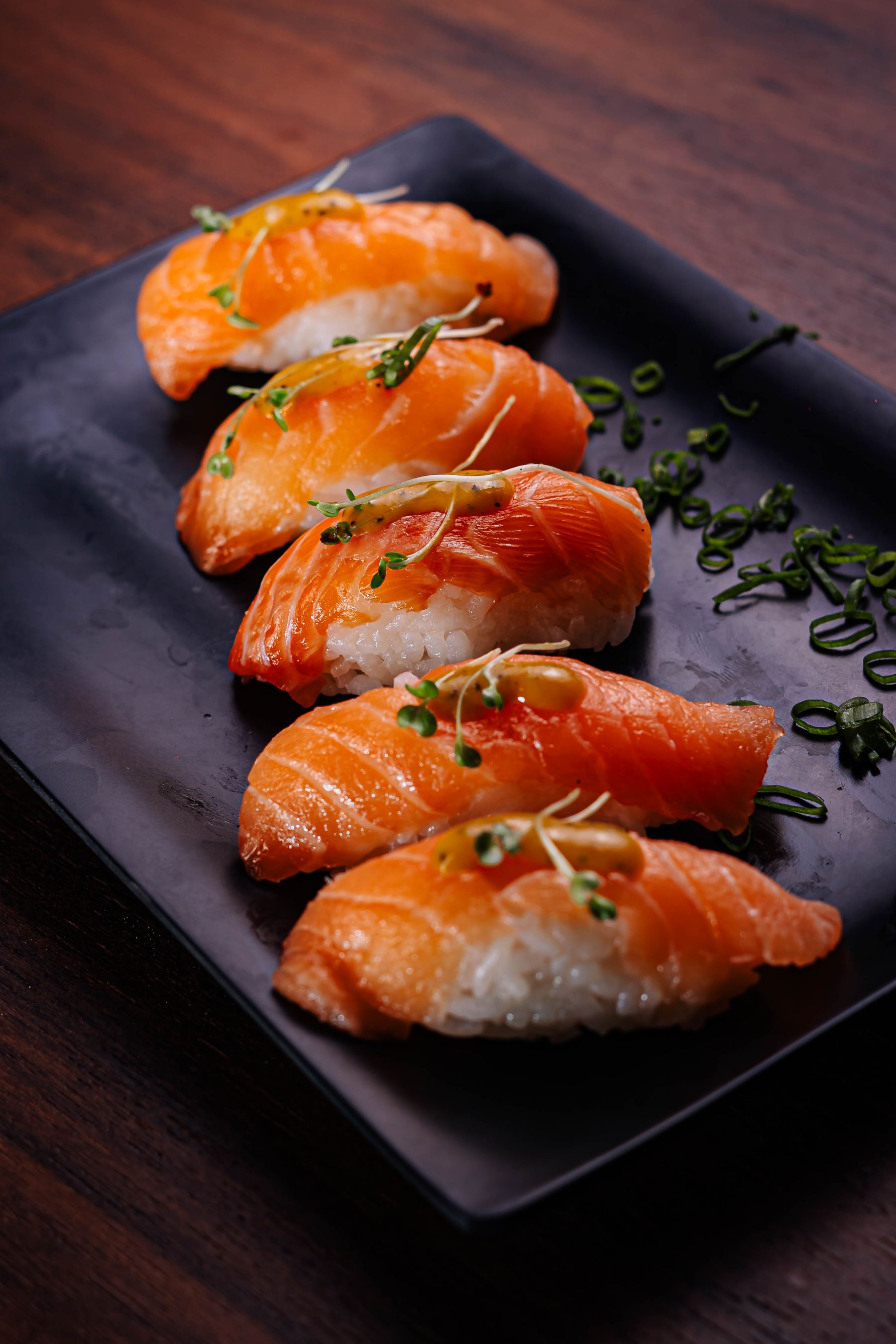 Salmon nigiri on a dark plate