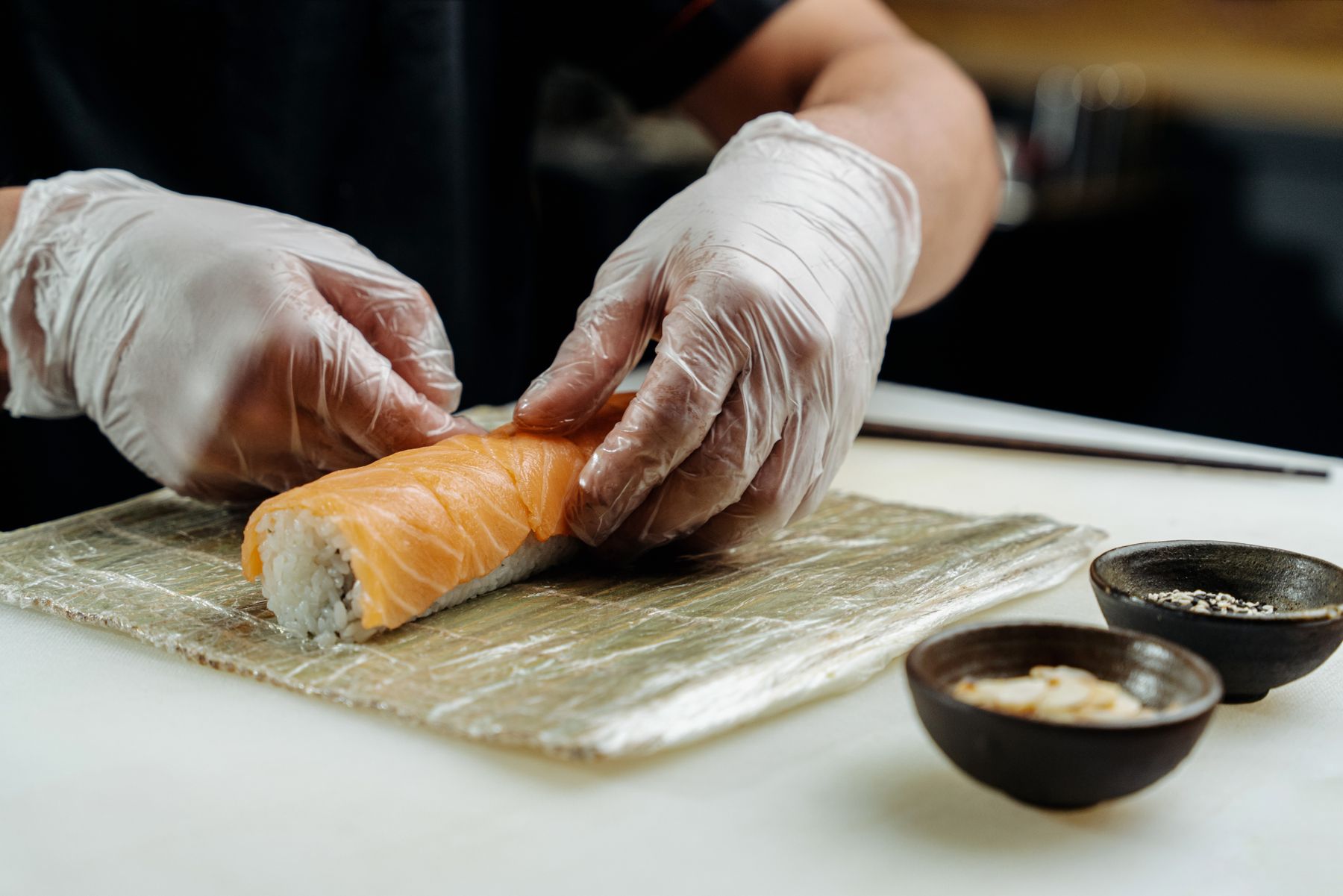Hands rolling sushi on a bamboo mat